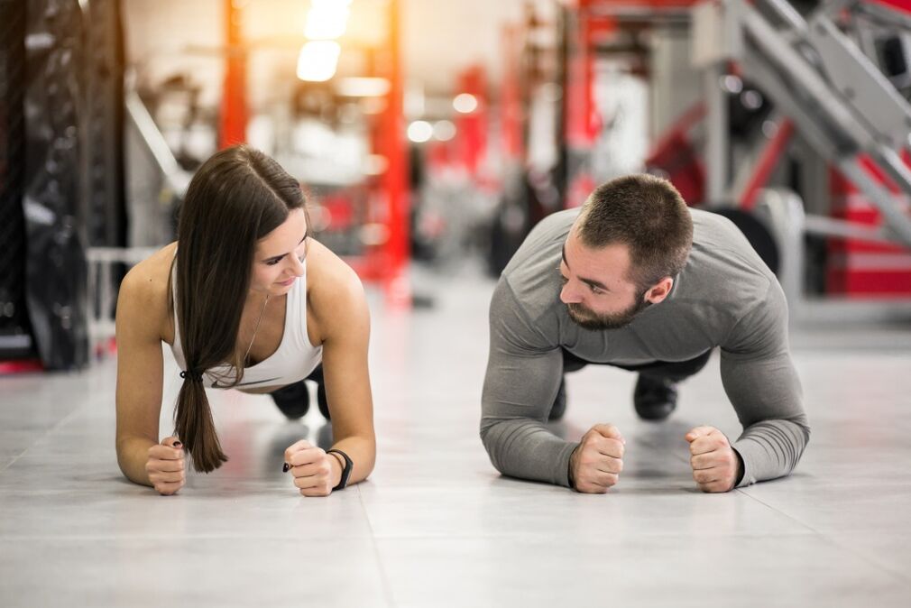 Um homem e uma mulher realizam o exercício de prancha projetado para todos os grupos musculares